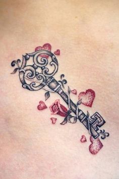 a tattoo on the back of a woman's stomach with an old key and hearts