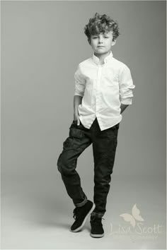 a young boy is posing for a black and white photo with his hands in his pockets