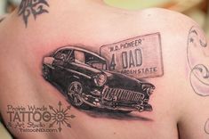 the back of a woman's shoulder with tattoos on it and an old car