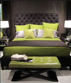 a bed with green sheets and pillows on top of it next to two nightstands