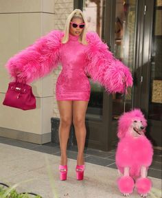 a woman in pink is walking her poodle