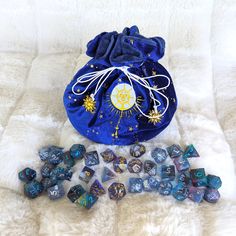 a blue bag filled with dice and other items on top of a white fur covered surface