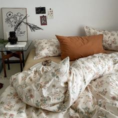 an unmade bed with many pillows and blankets on it in a room that is decorated with pictures