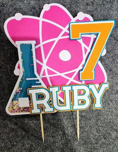 a cake topper with the number seven on it and an image of a pink flower