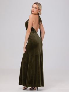 a woman in a long green dress is looking back at the camera and she has her hands on her hips