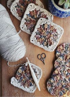 crocheted coasters, yarn and scissors on a wooden table with pot holders