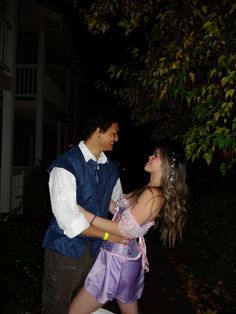 a man and woman dressed up in costume standing next to each other outside at night