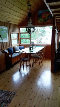 a living room with wood floors and wooden walls, along with a dining table surrounded by four chairs