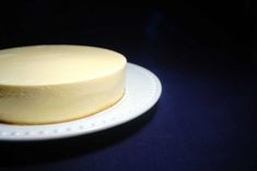 a white cake sitting on top of a white plate next to a blue tablecloth