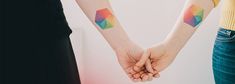 two people holding hands with colorful tattoos on their arms and one is holding the other's hand