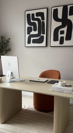 a desk with a laptop on it in front of two pictures