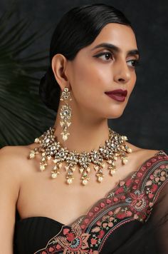 Kundan Necklace Set with Shell Pearls Necklace set with intricately cut Kundan stones put together in a beautiful floral design. The main kundan at its bottom has elegantly cut teardrop-shaped Kundan embellished with Shell Pearls. The earrings follow the same beautiful pattern, with a Pearl at the bottom and precisely cut Kundan stones set in a floral pattern. It's perfect for an elegant classy look or a minimalist style. The beautiful design is sure to fetch you compliments for such a tasteful Ornate Kundan Necklace For Reception, Festive Kundan Jewelry Sets With Elegant Design, Ornate Kundan Necklace With Cutdana, Festive Kundan Temple Necklace With Elegant Design, Kundan Chandbali Bridal Necklace With Elegant Design, Ornate Kundan Jewelry Sets For Diwali, Kundan Temple Bridal Necklace With Elegant Design, Kundan Bridal Necklace In Temple Style, Elegant Kundan Bridal Necklace In Temple Jewelry Style