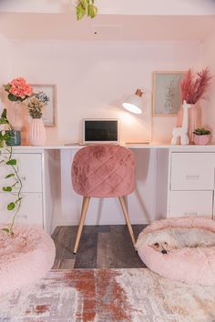 a pink chair and desk in a room with white drawers, rugs and plants