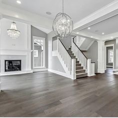 an empty living room with wood floors and chandelier