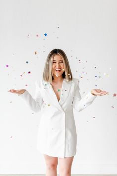 a woman standing in front of confetti falling from her mouth and hands out