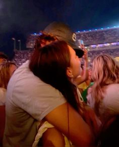 a man and woman kissing in front of a crowd at a baseball game with lights on the bleachers