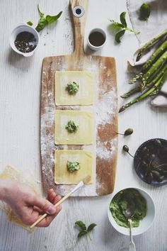 someone is making ravioli with pesto and parmesan cheese on a cutting board