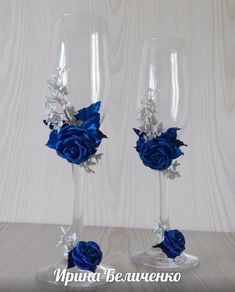 two wine glasses decorated with blue roses and silver leaves