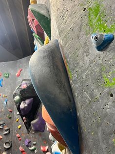 a person climbing up the side of a wall with colorful rocks and paint on it