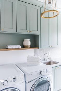 a washer and dryer in a room with green cabinets, white counter tops and gold accents