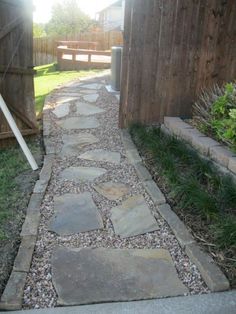 a stone path in front of a wooden fence