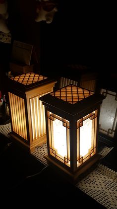 two lit lanterns sitting on top of a table