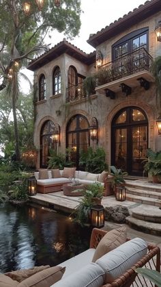 an outdoor living area with couches and tables next to a pool in front of a house