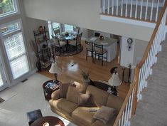 an overhead view of a living room and dining room with stairs leading up to the second floor