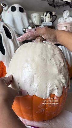 someone is decorating a pumpkin with white icing on the outside and orange inside