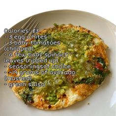 a white plate topped with an omelet covered in guacamole