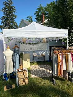 a tent with clothes hanging from it's sides on display in the grass near other tents