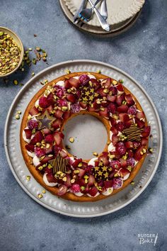 a cake with strawberries and other toppings sits on a plate next to two forks