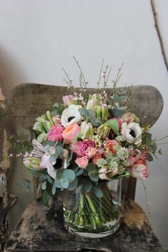 a vase filled with lots of flowers on top of a wooden table next to a chair