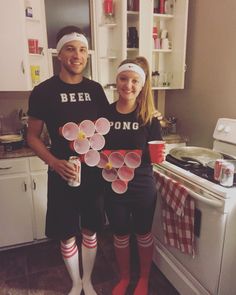 a man and woman standing next to each other in the kitchen with paper flowers on them