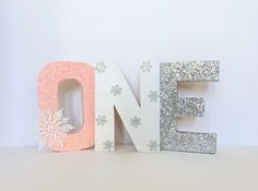 the word noel spelled with glitter and snowflakes on it's sides in front of a white background