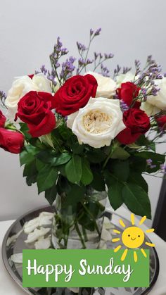 a vase filled with red and white roses sitting on top of a table next to a sign that says happy sunday