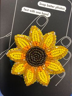 an orange and yellow flower brooch sitting on top of a piece of plastic material