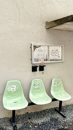 three green chairs sitting next to each other in front of a wall with pictures on it