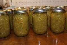 several jars filled with green stuff sitting on top of a wooden table