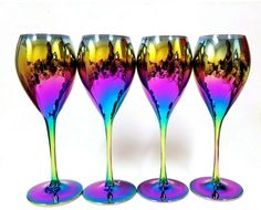 four colorful wine glasses are lined up against a white background