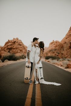 a man and woman kissing on the road with their skateboards