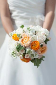 a bride holding a bouquet of white and orange flowers