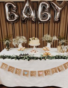 a table topped with cake and desserts next to balloons that read baby boy or girl