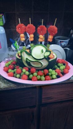 a cake made to look like a frog on a plate with grapes and carrots