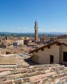 the rooftops of an old town with a clock tower in the background