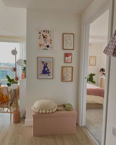 a white room with pictures on the wall and a pink bench in front of it