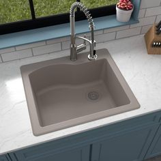 a gray sink sitting on top of a white counter next to a wooden cutting board