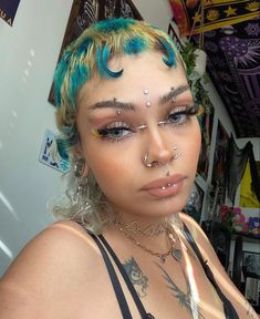 a woman with bright blue hair and piercings on her face is posing for the camera