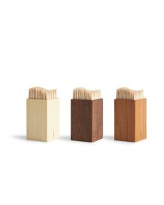 three wooden boxes with toothpicks in them on a white background, one is empty