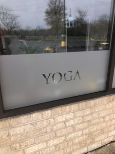 there is a sign that says yoga on the side of a building in front of a window